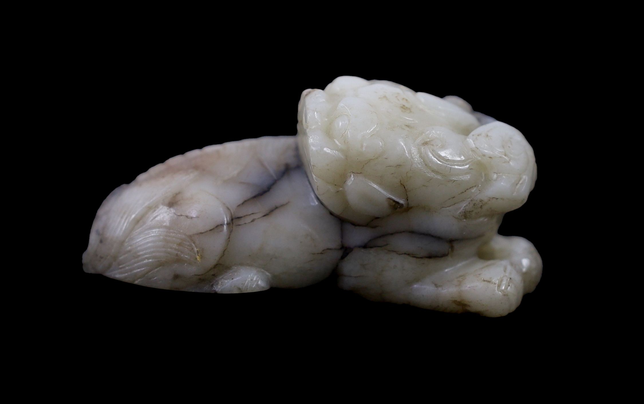 A Chinese Ming white and black jade figure of a recumbent beast, 6.8 cm long